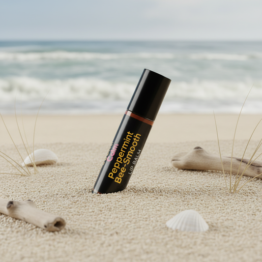 Bottle of peppermint balm on a sandy beach with ocean in the background