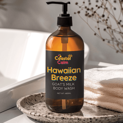 Bottle of Coastal Calm Hawaiian Breeze Goats Milk Body Wash on a textured surface with a blurred background